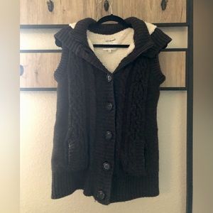 Brown sweater vest with cream fleece hood.